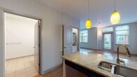 Located at 1055 Stratford Ave in Stratford, Connecticut, this single-floor residence offers a thoughtfully designed layout with a clean, modern aesthetic throughout. The open-concept living area is immediately welcoming, characterized by gleaming hardwood floors that extend through the main living spaces and large windows that invite generous amounts of natural light, offering pleasant views of the surrounding neighborhood. A pendant light fixture adds a warm, inviting focal point to the living and kitchen area.

The kitchen is well-appointed with dark espresso cabinetry lining both walls, granite countertops, and stainless steel appliances including an electric range, built-in microwave, dishwasher, and full-sized refrigerator. A bold teal accent wall adds a vibrant contrast to the cabinetry, creating a stylish and functional cooking space with hardwood flooring underfoot.

A dedicated laundry closet houses a stacked washer and dryer unit, providing added convenience within the home. The bathroom is finished with light tile flooring, a combination tub and shower with tiled surround, and a dark-cabinetry vanity that complements the home's consistent design language. The overall ambiance is modern, clean, and practical, making this a comfortable and move-in-ready space.