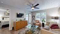 This efficiently designed one-bedroom, one-bathroom residence offers a thoughtfully organized single-floor layout that maximizes every square foot. The living room serves as the heart of the home, featuring hardwood-style flooring, a textured ceiling with a ceiling fan, and large sliding glass doors alongside wide windows that flood the space with natural light and provide views of the outdoors. The kitchen is outfitted with crisp white cabinetry, stainless steel appliances including a refrigerator, range, and dishwasher, light stone countertops, and a skylight that enhances the bright, clean aesthetic. The bedroom is a comfortable retreat with its own ceiling fan, a window with outdoor views, and direct access to a dedicated closet with built-in shelving for organized storage. The bathroom is finished in a neutral palette with wood-look tile flooring, a combined tub and shower, and a white vanity with ample counter space. Throughout the residence, consistent hardwood-style flooring, neutral wall tones, and thoughtful design details create a cohesive and inviting living environment.