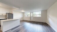 Located at 105 Rowena Dr in Toronto's M3A neighbourhood, this thoughtfully updated unit offers a clean, modern aesthetic across a comfortable single-floor layout with two bedrooms and one bathroom. The open-concept kitchen and living area forms the heart of the unit, with the kitchen featuring crisp white cabinetry, a subway tile backsplash, light quartz-style countertops, and a full suite of stainless steel appliances including a range, dishwasher, and refrigerator. Warm hardwood-style flooring runs throughout the kitchen, complemented by a practical breakfast bar peninsula. The spacious living room is bathed in natural light from a wide bank of windows overlooking neighbourhood greenery, and features baseboard heating and the same durable hardwood-style flooring. Both bedrooms are generously sized, with the primary bedroom offering ample space and a double-door closet. The second bedroom also includes a double closet and a window with natural light. The bathroom is finished with elegant marble-patterned tiling surrounding a full soaker tub and shower. A connecting hallway ties all rooms together in a clean, functional layout suited for comfortable everyday living.