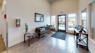 This single-floor amenity facility is thoughtfully designed to serve as a functional and comfortable shared space. The entrance features a bright, high-ceilinged lobby with large windows that allow natural light to flood in, offering views of the exterior surroundings. The lobby is furnished with stylish dark-framed seating, accent plants, a wall-mounted mirror, and polished concrete flooring, creating a welcoming first impression.

The central gathering area serves as both a dining and lounge space, featuring multiple high-top tables paired with black cross-back chairs arranged throughout the room. Polished concrete floors, recessed lighting, and wall-mounted televisions contribute to a clean, modern aesthetic. Large windows provide ample natural light and outward views, while a wall clock and framed artwork add character to the space.

Adjacent to the gathering area is a compact kitchenette, equipped with dark cabinetry, light countertops, a full-size refrigerator, microwave, coffee maker, and toaster oven — offering practical food and beverage preparation capabilities.

A dedicated fitness room rounds out the facility, housing treadmills, an elliptical, a stair climber, and free weights, all set on polished concrete floors beneath recessed lighting, providing a well-equipped space for exercise.