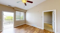 This single-floor unit offers a well-designed open-concept layout that seamlessly connects the kitchen and living areas. Vaulted ceilings throughout the main living space create a sense of openness and volume, complemented by a ceiling fan that adds both function and style. The living area features warm hardwood-style flooring, neutral beige walls, and generous natural light flowing in through large windows fitted with horizontal blinds. A sliding door provides direct access to a private balcony with outdoor views of surrounding greenery.

The kitchen is appointed with rich medium-toned wood cabinetry, granite-style countertops, a double stainless steel sink, and white appliances including an electric range with overhead microwave. A peninsula counter serves as a natural divider between the kitchen and living space, offering additional prep and seating potential.

The bathroom features a full tub-and-shower combination, a wood-vanity with a granite-topped single sink, a large mirror, and consistent hardwood-style flooring. Additional rooms accessible from the main living area include a carpeted bedroom and a closeted storage space, completing a functional and cohesive floor plan. The overall ambiance is clean, neutral, and move-in ready.