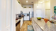 Located at Park 3400 on Davie Road in Davie, Florida, this single-level two-bedroom, two-bathroom residence offers a well-appointed interior with contemporary finishes throughout. The kitchen is a standout feature, showcasing crisp white cabinetry extending to the ceiling, granite countertops, a classic subway tile backsplash, wood-look flooring, and a full suite of stainless steel appliances including a range, microwave, dishwasher, and refrigerator. A generous island provides additional prep and serving space. The primary bedroom is a serene retreat with plush carpeting, natural light streaming through large windows framing views of tropical palm trees, and ample room for a full furniture arrangement. Its en-suite bathroom features a granite-topped vanity, white cabinetry, wood-look flooring, and a walk-in glass shower. The second bedroom is equally comfortable, with soft carpeting, natural light, and lush greenery views. The second bathroom mirrors the refined aesthetic with a granite vanity, a soaking tub with shower, and coordinating finishes. Recessed lighting, neutral tones, and consistent modern detailing create a cohesive and welcoming ambiance throughout the entire residence.