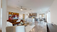 This thoughtfully designed single-floor residence offers an open-concept layout that seamlessly connects the living, dining, and kitchen areas, creating a bright and airy atmosphere enhanced by large windows and abundant natural light. Light-toned hardwood flooring flows throughout the main living spaces, lending warmth and visual continuity.

The kitchen is well-equipped with stainless steel appliances, including a refrigerator, range, microwave, and dishwasher, complemented by sleek, taupe cabinetry and a white waterfall-edge island with bar seating — ideal for casual dining or entertaining. Pendant lighting and recessed fixtures add a polished finish.

The dining area, positioned adjacent to the kitchen, benefits from generous window exposure and opens naturally into the living room, which features a ceiling fan, vibrant wall art, and large windows framing outdoor greenery views.

The bedroom is a serene retreat with plush carpeting, a ceiling fan, and windows that invite natural light. A generously sized walk-in closet with wire shelving systems provides practical, organized storage.

The bathroom is clean and modern, featuring a wide vanity with an undermount sink, wood-toned cabinetry, large-format tile, and a tub-shower combination. Throughout the residence, the design balances contemporary style with everyday functionality.