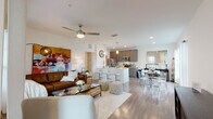 This thoughtfully designed single-floor residence offers an open-concept layout that seamlessly connects the living, dining, and kitchen areas, creating a bright and airy atmosphere enhanced by large windows and abundant natural light. Light-toned hardwood flooring flows throughout the main living spaces, lending warmth and visual continuity.

The kitchen is well-equipped with stainless steel appliances, including a refrigerator, range, microwave, and dishwasher, complemented by sleek, taupe cabinetry and a white waterfall-edge island with bar seating — ideal for casual dining or entertaining. Pendant lighting and recessed fixtures add a polished finish.

The dining area, positioned adjacent to the kitchen, benefits from generous window exposure and opens naturally into the living room, which features a ceiling fan, vibrant wall art, and large windows framing outdoor greenery views.

The bedroom is a serene retreat with plush carpeting, a ceiling fan, and windows that invite natural light. A generously sized walk-in closet with wire shelving systems provides practical, organized storage.

The bathroom is clean and modern, featuring a wide vanity with an undermount sink, wood-toned cabinetry, large-format tile, and a tub-shower combination. Throughout the residence, the design balances contemporary style with everyday functionality.