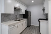 Located at 1776 N Sycamore Ave, Unit 207, in the heart of Los Angeles' vibrant Hollywood neighborhood, this thoughtfully updated residence offers a clean, modern aesthetic throughout. Light wood-style flooring flows seamlessly across all living areas, creating a cohesive and airy feel complemented by crisp white walls and recessed lighting.

The open living area provides generous room for furnishings and connects naturally to the kitchen, which features white shaker cabinetry, quartz countertops, a stainless steel undermount sink, a mosaic tile backsplash, and stainless steel appliances including a gas range and refrigerator. A breakfast bar adds convenience for casual dining.

The bedrooms are well-proportioned, each featuring large windows dressed with vertical blinds that allow for excellent natural light control. One bedroom includes a mirrored sliding-door closet, providing practical storage. Additional rooms offer similar bright, neutral environments adaptable to various uses.

The bathroom is finished to a high standard, featuring a tub-shower combination enclosed by a glass sliding door and clad in elegant marble-look tile with a built-in niche. A white vanity and coordinating flooring complete the polished look. The unit's overall design prioritizes clean lines, functionality, and a bright, welcoming ambiance throughout.