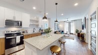 This well-appointed single-floor residence at 1290 Old Peachtree Rd NW in Duluth, Georgia, offers a thoughtfully designed open-concept layout with modern finishes throughout. The kitchen serves as the heart of the home, showcasing granite countertops, a large central island with seating, two-tone cabinetry combining crisp white upper cabinets with warm wood lower cabinets, and a classic subway tile backsplash. Stainless steel appliances, including a french door refrigerator, range, microwave, and dishwasher, complete this functional and stylish culinary space. Pendant lighting above the island adds a refined touch. The kitchen flows seamlessly into the living area, which features warm hardwood-style flooring, large windows with blinds, access to an outdoor area via glass doors, and a ceiling fan that enhances comfort. The bedrooms are carpeted and bright, each benefiting from generous natural light through wide windows dressed with layered blinds and curtains. The primary bathroom includes a granite-topped wood vanity and a glass-enclosed walk-in shower, with direct access to a walk-in closet. A secondary bathroom mirrors the same refined aesthetic with a matching vanity and tub-shower combination. The overall ambiance is modern, clean, and cohesive throughout.