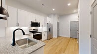 Located at 34 Ramsey Branch Rd in Freeport, FL, this thoughtfully designed single-floor home offers a comfortable and functional layout with modern finishes throughout. Light hardwood flooring flows through the main living areas, complemented by crisp white walls and recessed lighting that create a bright, clean aesthetic.

The kitchen is a standout feature, showcasing white shaker-style cabinetry with matte black hardware, granite countertops, and a herringbone tile backsplash. A peninsula with an integrated sink and pendant lighting above provides additional prep and dining space, while a full suite of stainless steel appliances — including a side-by-side refrigerator, electric range, over-the-range microwave, and dishwasher — rounds out this well-equipped space. Natural light from a large window at the far end of the kitchen and living area adds to the open, airy feel.

The bedroom features plush carpeting and a generously sized window with views of the surrounding greenery, offering a calm, private retreat. The bathroom continues the refined finishes with a granite-topped vanity, a soaking tub with large-format tile surround, built-in shelving, and hardwood-style flooring. Three closets — including a spacious walk-in — provide ample storage, and a dedicated laundry area adds everyday convenience.