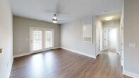 Located at 1475 Chatham Parkway in Savannah, GA, this well-appointed 3-bedroom, 3-bathroom residence offers a thoughtfully designed single-floor layout with a clean, modern aesthetic throughout. The open-concept living area features hardwood-style flooring and a ceiling fan, with natural light streaming in through French doors that lead to a private outdoor patio. The kitchen is a standout feature, showcasing white shaker cabinetry, dark countertops, a subway tile backsplash, stainless steel appliances including a refrigerator, range, and microwave, and a central island illuminated by pendant lighting. A dedicated laundry room with a washer and shelving adds everyday convenience. The three bedrooms are finished with neutral-toned carpet and bright white walls, creating a calm and versatile environment. The primary bedroom is a comfortable, well-proportioned retreat. Each of the three bathrooms features white shaker-style vanity cabinetry, dark countertops, hardwood-style flooring, and modern light fixtures with mirrors. Two closets provide ample storage throughout. Neutral gray walls and white trim carry a cohesive, contemporary palette across all rooms, giving the entire space a fresh and move-in-ready feel.