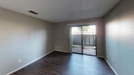 This single-story residence at Valle Vista in Vallejo, California offers a practical and well-organized layout across multiple rooms. The living area features dark wood-style flooring and neutral gray walls beneath a textured ceiling, with a ceiling fan providing added comfort. A sliding glass door opens directly to a private outdoor patio, filling the space with natural light and providing convenient outdoor access.

The kitchen is designed with an open, semi-enclosed layout that connects seamlessly to the living area. White cabinetry, granite-style countertops, a stainless steel refrigerator, and a dishwasher provide both style and functionality. A peninsula counter serves as a natural divider between the kitchen and the main living space.

The bedrooms are carpeted and finished with the same neutral gray tones found throughout the unit. Each room features a window with exterior views and a flush-mount ceiling light fixture, creating a bright and comfortable environment.

The bathroom includes a full tub-shower combination with a curved curtain rod, complemented by textured walls and wood-style flooring. Throughout the unit, consistent finishes and a cohesive neutral palette contribute to a clean, move-in-ready ambiance.