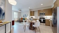 Located at 40445 Portola Ave in Palm Desert, California, this well-appointed two-bedroom, two-bathroom residence offers a thoughtfully designed open-concept layout. The main living area seamlessly connects the kitchen, dining, and living spaces, creating an efficient and welcoming environment. Light-toned flooring runs throughout the common areas, enhancing the bright, airy atmosphere complemented by recessed lighting and a ceiling fan.

The kitchen is equipped with stainless steel appliances — including a range, microwave, dishwasher, and refrigerator — and features warm wood cabinetry, a white tile backsplash, and ample counter space. A round dining table sits adjacent to the kitchen, making everyday meals and entertaining equally convenient. The living room opens to a private outdoor balcony, bringing in natural light and outdoor views.

The primary bedroom offers a comfortable retreat with carpeted flooring, neutral tones, and a walk-in closet with built-in shelving. The bathrooms are finished with large-format tile, wood-toned vanity cabinetry, white quartz countertops, and a glass-enclosed walk-in shower. A hallway connects the bedrooms and bathrooms, adding to the home's functional flow. The space combines modern design with practical livability in the heart of the Coachella Valley.