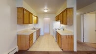 Located at 307 N Prairieview Rd in Mahomet, IL, this single-floor unit offers a functional and straightforward layout suited for comfortable everyday living. The galley-style kitchen is well-equipped with ample warm-toned wooden cabinetry lining both walls, generous counter space, a double sink, and white appliances including a range and refrigerator. Tile flooring runs throughout the kitchen, which connects conveniently to additional storage space via a closet door. The living area features soft carpeting, a ceiling fan with light fixture, and a front entry door, creating a welcoming arrival space. A second main room provides sliding glass door access to the outdoors, filling the space with natural light, and is also equipped with a ceiling fan and baseboard heating. The bedrooms are carpeted and bright, each featuring windows that bring in natural light, ceiling fans, and baseboard heating units. The bathroom includes a single vanity with a large mirror, wood cabinetry below, tile surround near the shower/tub area, and a textured ceiling consistent throughout the unit. Overall, the space presents a practical, no-frills layout with consistent finishes and functional amenities throughout.