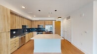 This contemporary 1,110 square foot apartment in Atlanta offers a harmonious blend of style and functionality. The open-concept layout seamlessly integrates the living room and kitchen, creating an expansive feel. The kitchen is a highlight, featuring sleek wood cabinetry, contrasting dark countertops, and stainless steel appliances, including a side-by-side refrigerator.

Both bedrooms are generously sized, with the primary bedroom measuring 140 square feet. Large windows in the bedrooms provide ample natural light and stunning city views. The bathrooms are modern and elegant, with one showcasing a double vanity with illuminated mirrors and ample storage.

Throughout the apartment, warm wood-tone flooring adds warmth and continuity. The living areas are adorned with ceiling fans, enhancing comfort and air circulation. Closet space is plentiful, with well-designed walk-in closets featuring built-in shelving and hanging rods.

The apartment's neutral color palette, primarily whites and light woods, creates a bright, airy atmosphere that serves as a perfect canvas for personal decor. High ceilings and recessed lighting further contribute to the sense of spaciousness and modernity. This thoughtfully designed space offers a perfect balance of comfort and contemporary urban living.