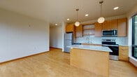 Located at 401 N Lawn Ave in Madison, Wisconsin, this single-floor residence offers a thoughtfully designed open-concept layout that seamlessly connects the kitchen and living areas. Light wood flooring runs throughout the space, lending warmth and continuity to each room.

The kitchen is a standout feature, outfitted with warm-toned wood cabinetry, white tile backsplash, and a full suite of stainless steel appliances including a refrigerator, range, microwave, and dishwasher. A central kitchen island with a clean white countertop provides additional workspace and serves as a natural gathering point. Overhead, globe pendant lights add a modern, inviting touch, while recessed lighting ensures the space is well-lit throughout.

The open living area flows naturally from the kitchen, offering generous space and a clean, minimalist aesthetic. Large windows bring in abundant natural light and frame views of the surrounding neighborhood, creating a bright and airy atmosphere.

The bedroom continues the light wood flooring and features a sizable window that fills the room with daylight and offers views of the adjacent urban landscape. The bathroom includes a clean, white soaking tub and tiled surround, maintaining the space's consistent, modern sensibility. Overall, this residence combines functional design with contemporary finishes for comfortable everyday living.