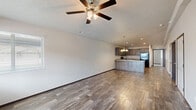 This single-story, 2-bedroom, 1-bathroom unit offers a practical and cohesive layout designed for comfortable everyday living. The open-concept living and kitchen area forms the heart of the home, where wood-look plank flooring extends throughout and a ceiling fan with light fixture anchors the living space. Natural light filters in through windows with views of the surrounding neighborhood, complementing the bright, neutral-toned walls.

The kitchen is well-equipped with rich, dark-stained cabinetry providing ample storage, light granite-style countertops, and a full suite of black appliances including a refrigerator, electric range, microwave, and a peninsula with an integrated sink. Recessed and pendant lighting enhances both function and ambiance in this area.

Both bedrooms feature plush carpeting and ceiling fans. The primary bedroom includes access to a dedicated closet with built-in shelving, while the secondary bedroom benefits from a window admitting natural light. The full bathroom features wood-look tile flooring, a vanity, and a tub-shower combination. A dedicated laundry space houses a full-size washer and dryer. A hallway efficiently connects all rooms within the unit.