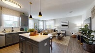 This single-floor residence at 100 Oakview Dr in Trumbull, Connecticut, offers a thoughtfully designed open-concept layout that seamlessly connects the kitchen, dining, and living areas. The kitchen is a standout feature, showcasing gray shaker-style cabinetry, white quartz countertops, a classic subway tile backsplash, and a full suite of stainless steel appliances including a gas range, built-in microwave, dishwasher, and French door refrigerator. A central island with pendant lighting provides additional prep space and casual seating. The living area is bright and spacious, with wood-look flooring flowing throughout and large windows that invite abundant natural light. A dedicated dining nook, surrounded by multiple windows with sheer curtains, creates an airy and pleasant space for meals. The bedroom features wood-look flooring, neutral walls, and access to a generous walk-in closet. Two bathrooms serve the residence: one with a glass-enclosed walk-in shower and tiled surround, and another with a tub-shower combination — both finished with gray vanities, white countertops, and tile flooring. The overall aesthetic is modern and cohesive, with warm metallic accents and a neutral color palette throughout.