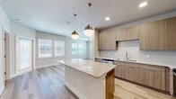 Located on Narcoossee Road in Orlando, FL, this thoughtfully designed single-story residence offers 2 bedrooms and 3 bathrooms within a well-appointed floor plan. The open-concept kitchen and living area serves as the heart of the home, featuring a large granite island with pendant lighting, flat-panel wood cabinetry, tile backsplash, and a full suite of stainless steel appliances including a range, over-the-range microwave, and refrigerator. Light hardwood-style flooring flows through the main living areas and hallways, complemented by neutral-toned walls that enhance the bright, airy atmosphere. Natural light fills the space through multiple windows dressed with blinds. The primary bedroom is generously sized, finished with plush carpet and a ceiling fan, and connects to an en-suite bathroom and a walk-in closet with wire shelving. The second bedroom also features hardwood-style flooring, a ceiling fan, and natural light from dual windows. Two additional bathrooms serve the home. A dedicated laundry room accommodates a full-size washer and dryer. Clean lines, modern finishes, and a practical layout define this move-in-ready Orlando residence.