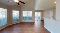 This 936 square foot apartment offers a thoughtful blend of comfort and functionality. The living area boasts vaulted ceilings, creating an open and airy atmosphere. Large windows with horizontal blinds flood the space with natural light, while providing privacy when needed. A focal point of the living room is the brick-framed fireplace, adding warmth and character.

The kitchen features wooden cabinetry, granite countertops, and modern black appliances, including a spacious refrigerator. The galley-style layout maximizes efficiency and storage space. Both bedrooms are generously sized, with plush carpeting and ceiling fans for comfort. The bathrooms are well-appointed, featuring tub-shower combinations with tiled surrounds, and vanities with ample counter space.

Throughout the apartment, you'll find a mix of rich hardwood flooring in the main living areas and soft carpeting in the bedrooms. Multiple ceiling fans ensure good air circulation. The overall color palette is neutral, allowing for personal decorating preferences. This apartment combines practical amenities with an inviting ambiance, making it an ideal living space for various lifestyles.