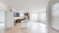 This well-appointed 2-bedroom, 3-bathroom single-floor residence offers a thoughtfully designed open-concept layout with contemporary finishes throughout. The kitchen is a standout feature, equipped with dark gray shaker-style cabinetry, stainless steel appliances including a refrigerator, range, and microwave, a subway tile backsplash, and a large curved island topped with granite countertops and pendant lighting. Light wood-style flooring flows seamlessly from the kitchen into the bright and airy living area, which benefits from multiple windows and a ceiling fan. An entry hallway includes a built-in mudroom nook with overhead cabinetry and bench seating, providing practical storage space alongside two dedicated closets. The primary bedroom is a comfortable retreat featuring plush carpeting, a ceiling fan, and access to a private en-suite bathroom. The primary bath showcases granite countertops, white cabinetry with modern hardware, a framed mirror, and a walk-in closet with built-in shelving and hanging rods. The second bedroom also features carpeted flooring and ample natural light. Bathrooms throughout the residence feature large-format tile flooring and clean, modern fixtures, maintaining a consistent and polished aesthetic across the entire space.