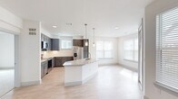 This well-appointed 2-bedroom, 3-bathroom single-floor residence offers a thoughtfully designed open-concept layout with contemporary finishes throughout. The kitchen is a standout feature, equipped with dark gray shaker-style cabinetry, stainless steel appliances including a refrigerator, range, and microwave, a subway tile backsplash, and a large curved island topped with granite countertops and pendant lighting. Light wood-style flooring flows seamlessly from the kitchen into the bright and airy living area, which benefits from multiple windows and a ceiling fan. An entry hallway includes a built-in mudroom nook with overhead cabinetry and bench seating, providing practical storage space alongside two dedicated closets. The primary bedroom is a comfortable retreat featuring plush carpeting, a ceiling fan, and access to a private en-suite bathroom. The primary bath showcases granite countertops, white cabinetry with modern hardware, a framed mirror, and a walk-in closet with built-in shelving and hanging rods. The second bedroom also features carpeted flooring and ample natural light. Bathrooms throughout the residence feature large-format tile flooring and clean, modern fixtures, maintaining a consistent and polished aesthetic across the entire space.