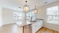 Located at 425 Devon Bryan St. in Columbus, OH, this well-appointed 1-bedroom, 1-bathroom residence offers a thoughtfully designed single-floor layout. The open-concept living area seamlessly connects the kitchen, dining, and living spaces, creating an efficient and inviting environment. The kitchen is a standout feature, showcasing granite countertops, crisp white shaker cabinetry, a decorative arabesque tile backsplash, and a full suite of stainless steel appliances including a refrigerator, range, microwave, and dishwasher. A central island with a double-basin sink is elegantly framed by two geometric pendant light fixtures, adding a modern touch. Light hardwood flooring flows throughout the main living areas, complemented by neutral wall tones that enhance the sense of brightness. Multiple windows with slatted blinds invite abundant natural light across the space. The bedroom is a comfortable retreat with a large window and hardwood flooring. The bathroom features large-format marble-look tile flooring, granite countertops, and white cabinetry. A walk-in closet with wire shelving provides generous storage. The unit also includes a dedicated laundry area, completing this functional and stylish home.