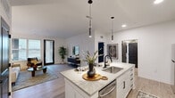 This thoughtfully designed 2-bedroom, 1-bathroom residence offers a seamless open-concept layout that connects the kitchen, dining, and living areas into one cohesive, light-filled space. The kitchen is a standout feature, showcasing crisp white shaker cabinetry extending to the ceiling, a classic subway tile backsplash, stainless steel appliances, and a large center island with quartz countertops and pendant lighting — ideal for both cooking and casual dining with bar seating. Light wood-look flooring flows throughout the main living areas, complementing the clean, neutral color palette and modern black hardware accents. The living room is generously proportioned, bathed in natural light from large windows and a glass-paneled exterior door that invites the outdoors in. The primary bedroom features plush carpeting, a walk-in closet with built-in shelving, and direct access to the well-appointed bathroom. The bathroom offers a white vanity with quartz countertop, an undermount sink with matte black fixtures, and a tiled tub-shower combination. The second bedroom provides comfortable, flexible space. Throughout the residence, high ceilings, recessed lighting, and a consistent modern aesthetic create a polished, welcoming ambiance.