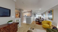 This thoughtfully designed single-floor residence offers a seamless blend of comfort and style across its open, flowing layout. The living area serves as the heart of the home, featuring crown molding, a ceiling fan, and a large sliding glass door that fills the space with natural light. The dining area sits adjacent, accented by a mirrored wall that amplifies the sense of space and reflects the warm tones throughout.

The kitchen is well-appointed with light wood cabinetry, white appliances including a range, microwave, and dishwasher, and a peninsula with a sink that opens toward the dining area — ideal for both everyday living and entertaining. Tile flooring extends through the kitchen for easy maintenance, while warm hardwood flooring defines the dining zone.

A hallway lined with built-in shelving connects the main living areas to the private quarters, providing convenient display and storage space. The bedroom is generously sized with plush carpeting, a ceiling fan, a large window with blinds and drapery, and crown molding that lends an elegant finish.

The bathroom features tile flooring, a vanity with light wood cabinetry, a large mirror, and a tub-shower combination. A dedicated in-unit laundry room with a full-size washer and dryer adds exceptional convenience to this well-rounded and inviting residence.