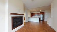 This single-floor residence showcases a well-designed open-concept layout that seamlessly connects the living area and kitchen. The living room is a bright, welcoming space highlighted by rich hardwood flooring, a ceiling fan, generous natural light from large windows and a glass-paneled exterior door, and a sleek fireplace with a wood-trimmed mantle as a central focal point.

The kitchen is appointed with rich, dark-stained wood cabinetry extending to the upper walls for ample storage, granite countertops, a white subway tile backsplash, and a full suite of stainless steel appliances including a French door refrigerator, gas range, and built-in microwave. A spacious peninsula with a granite surface and integrated sink provides additional workspace and casual seating.

The bedrooms feature neutral carpet and are served by a full bathroom equipped with a granite-topped vanity, a tub-shower combination, and tile flooring. One bedroom includes a dedicated walk-in closet. A dedicated laundry area accommodates a full-sized washer and dryer, completing this thoughtfully arranged single-level home.
