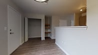 This two-floor residence offers a clean, modern aesthetic throughout, with thoughtful design details evident in every room. The main living area features light-toned wood-look flooring and a pair of windows that draw in generous natural light, creating an open and airy atmosphere. The galley-style kitchen is well-equipped with stainless steel appliances — including a gas range, microwave, refrigerator, and dishwasher — complemented by two-tone cabinetry, light countertops, and a double basin sink. The layout maximizes functionality within the space. The bedrooms are finished with plush carpet and feature large windows that offer outdoor views, filling each room with daylight. One bedroom area includes a closet with built-in rod storage alongside dedicated open shelving, providing versatile organization options. The bathrooms are finished with wood-look vinyl flooring and feature full tub-shower combinations with chrome fixtures and clean white surrounds. One bathroom includes a vanity with cabinetry in a warm wood tone. Throughout the space, neutral wall tones, white trim, and consistent flooring choices create a cohesive and move-in-ready environment that is both practical and inviting.