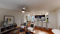 Located at 3000 Greenridge Dr in Houston, Texas, this single-floor residence offers a thoughtfully designed open-concept layout that seamlessly connects the living, dining, and kitchen areas. Rich hardwood flooring flows throughout the main living spaces, complemented by neutral walls and an abundance of natural light from large windows with outdoor views of lush greenery.

The kitchen is a standout feature, boasting dark espresso cabinetry, granite countertops, a tile backsplash, stainless steel appliances including a gas range and microwave, and track lighting overhead. A broad breakfast bar provides additional seating and connects the kitchen to the dining area, which opens to a private exterior door.

The living room is generously sized, accommodating multiple seating arrangements, and features a ceiling fan and windows that draw in natural light. A dedicated dining nook with additional wall space rounds out the common area.

The bedrooms are carpeted for comfort, each offering ceiling fans, ample natural light, and access to walk-in closets. The primary bedroom includes a dresser area and a sitting nook by the window. The bathroom is finished with dark cabinetry, granite countertops, tile flooring, and a full tub-shower combination, maintaining the home's consistent, modern aesthetic throughout.