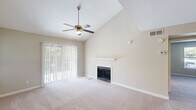 Located at 3214 Brassfield Rd in Greensboro, NC, this one-bedroom, one-bathroom residence offers a well-organized single-floor layout with thoughtful design details throughout. The living room is a standout, boasting soaring vaulted ceilings, a ceiling fan, a classic fireplace with a floating mantel shelf, and a sliding glass door that floods the space with natural light and provides views of lush greenery outside. Soft carpet underfoot adds warmth and comfort to this inviting area. The kitchen is thoroughly updated, featuring white shaker cabinets with matte black hardware, marble-look countertops, a subway tile backsplash, stainless steel appliances, and a peninsula with a stainless sink — all set atop light wood-look flooring. A dedicated entrance and hallway connect the main living areas to the generously sized bedroom, which offers vaulted ceilings, plush carpet, a ceiling fan, a walk-in closet, and direct access to the full bathroom. The bathroom includes a tub/shower combination with wood-look flooring. A conveniently located in-unit laundry area with shelving above completes this efficiently designed home.