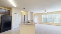 Located in Yulee, FL, this single-story, 3-bedroom, 2-bathroom home offers a well-designed open-concept layout that maximizes its comfortable footprint. The combined kitchen and living area serves as the heart of the home, where a peninsula with a double sink and laminate countertops connects the kitchen to the spacious living room. The kitchen is equipped with dark espresso cabinetry, black appliances including a refrigerator, range, and microwave, and easy-to-maintain tile flooring. The living room features soft carpeting, a ceiling fan with light fixture, and a large multi-pane window alongside a glass door that fills the space with abundant natural light.

The three bedrooms are carpeted and finished in warm neutral tones. The generously sized primary bedroom includes a walk-in closet with wire shelving and a private entrance to one of the two full bathrooms. Additional bedrooms are served by a second full bathroom, which features tile flooring, a vanity with dark cabinetry, and a tub-shower combination. Two closets throughout the home provide practical storage solutions. The consistent warm yellow-beige palette, ceiling fans, and plentiful natural light give this home a bright, inviting character throughout.