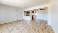 Located at 2433 W Campbell Ave in Phoenix, Arizona, this single-floor home offers a practical and comfortable layout across two bedrooms and two bathrooms. The open living area is bright and welcoming, featuring large tile flooring and a sliding window fitted with vertical blinds that allow ample natural light to fill the space. A ceiling fan adds to the comfort of the living area, which flows seamlessly into the kitchen through a half-wall pass-through. The kitchen is well-equipped with warm wood cabinetry, a double-basin stainless steel sink, a range, and a refrigerator, all set atop matching tile flooring. The two bedrooms feature rich wood-style laminate flooring and windows with outdoor views, giving each room a light and airy feel. The bathrooms each offer distinct configurations — one includes a full soaking tub with a shower surround, while the second features a tiled walk-in shower alongside a wood-vanity. Clean white walls throughout the home create a neutral and versatile backdrop. The overall ambiance is straightforward and functional, making this Phoenix home a solid and practical living space.