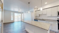 This well-appointed 2-bedroom, 1-bathroom residence offers a thoughtfully designed single-floor layout that maximizes functionality and style. The open-concept kitchen serves as the heart of the home, featuring crisp white shaker cabinetry, granite countertops, a central island with pendant lighting, and a full suite of stainless steel appliances including a refrigerator, range, microwave, and dishwasher. In-unit laundry is also accessible from this area. The kitchen flows seamlessly into the living area, which is finished with wood-style flooring, a ceiling fan, and sliding glass doors that open to a private balcony with outdoor views, filling the space with natural light. The primary bedroom is generously proportioned, offering a ceiling fan, a sliding glass door to the balcony, and a built-in closet with dual hanging rods for ample storage. The second bedroom is bright and comfortable, featuring a large window with blinds and a ceiling fan. The shared bathroom is well-finished with a double-sink granite vanity, white cabinetry, and a walk-in shower with built-in shelving. Wood-style flooring runs consistently throughout, lending a cohesive and modern aesthetic to the entire residence.