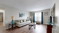 Located at 5418 Arbrook in Columbus, Ohio, this single-floor, 2-bedroom, 2-bathroom home offers a practical and well-organized layout. The combined living, dining, and kitchen area forms the heart of the home. The living room features wood-look flooring, a textured ceiling, and a large window that fills the space with natural light. The kitchen is equipped with white shaker-style cabinetry, granite-look countertops, black appliances including a range and refrigerator, and a double sink — providing ample workspace in a compact, efficient galley-style arrangement. The adjacent dining area comfortably accommodates a round table and includes a built-in shelving nook. The spacious primary bedroom is carpeted and includes an open closet with hanging storage. The second bedroom is also carpeted and benefits from neutral wall tones throughout. Both bathrooms feature wood-look flooring, white vanity cabinetry, framed mirrors, and a tub-shower combination. Additional conveniences include a dedicated laundry area, a utility room, a hallway connecting the private spaces, and four closets distributed throughout the home for generous storage. The overall ambiance is clean, bright, and functional.