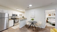 Located at 4013 Wilshire Blvd in Wilmington, NC, this single-floor, 2-bedroom, 2-bathroom residence offers a thoughtfully designed layout with a clean, modern aesthetic throughout. The open-concept kitchen and living area serves as the heart of the home, featuring white shaker cabinetry, granite countertops, stainless steel appliances including a refrigerator, microwave, and range, and a peninsula that provides additional prep and seating space. Wood-look flooring flows seamlessly through the main living areas, adding warmth and cohesion to the space. The living room is bright and inviting, with natural light filtering through large windows and French doors that open to an outdoor balcony area. Both bedrooms are comfortably proportioned, with the primary bedroom offering a ceiling fan, a dedicated closet, and a private en-suite bathroom. The second bedroom features its own closet and convenient access to the second full bathroom. Each bathroom is finished with granite-topped vanities, white cabinetry, and wood-look flooring. A dedicated laundry room with a full-size washer and dryer adds everyday convenience. With its light-filled interiors, functional layout, and quality finishes, this residence offers a comfortable and practical living experience in Wilmington.