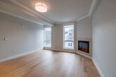 Located at 105 W Court St in the heart of Ithaca, NY, this thoughtfully designed residence offers three bedrooms and two full bathrooms across a single, well-organized floor. The open-concept living and kitchen area serves as the centerpiece of the home, featuring warm hardwood flooring, crown molding, and recessed lighting that create a clean, modern aesthetic. The kitchen is equipped with stainless steel appliances—including a refrigerator, electric range, and dishwasher—complemented by gray shaker-style cabinetry, under-cabinet lighting, and a white countertop peninsula that doubles as a casual dining or workspace. The spacious living area flows naturally from the kitchen, bathed in natural light. The primary bedroom features large windows with views of the surrounding Ithaca streetscape and neighboring historic architecture, along with hardwood flooring. The secondary bedrooms are carpeted and each include windows that bring in natural light. Both bathrooms are finished with large-format tile flooring, illuminated vanity mirrors, gray cabinetry, and walk-in showers, offering a clean and contemporary feel. A hallway with louvered closet doors connects the living spaces to the bedrooms, adding functional storage throughout this efficiently designed home.