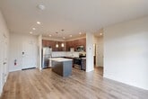 This thoughtfully designed 2-bedroom, 2-bathroom residence in South Burlington, Vermont, offers a functional and modern single-floor layout. The open-concept living, dining, and kitchen area forms the heart of the home, featuring light-toned hardwood-style flooring that flows throughout. The kitchen is well-equipped with rich dark cabinetry, white countertops, a full suite of stainless steel appliances including a refrigerator, electric range, microwave, and dishwasher, along with a center island with pendant lighting overhead — ideal for both meal prep and casual dining.

Large windows in the living area and bedrooms flood the space with natural light and provide views of mature trees outside, creating a serene atmosphere. Both bedrooms are comfortably sized, with the primary bedroom offering a dedicated closet and easy access to one of two full bathrooms. Each bathroom mirrors the home's design language with dark wood vanities, white countertops, and hardwood-style flooring.

Three closets provide ample storage throughout, while a dedicated laundry area adds everyday convenience. Recessed lighting and a clean, neutral color palette give the space a bright, contemporary feel throughout.