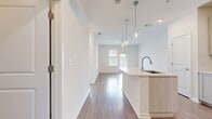 Located at 8000 Essex Point Circle in Orlando, FL 32819, this well-appointed 630 square foot apartment offers 1 bedroom and 3 bathrooms across a single floor. The open-concept kitchen and living area is anchored by a modern kitchen featuring light wood shaker-style cabinetry, white quartz countertops, a tile backsplash, and a full suite of stainless steel appliances including a refrigerator, electric range, and over-the-range microwave. Light hardwood-style flooring flows throughout the main living areas, complementing the bright, neutral color palette. The living room is airy and sun-filled, with a ceiling fan, hardwood floors, and a glass door providing natural light and outdoor views. The 150 square foot primary bedroom is carpeted for comfort, features a ceiling fan, and is filled with natural light from a large window. The bathrooms are finished with light wood vanities, white countertops, hardwood-style flooring, and a soaking tub. A dedicated in-unit laundry room houses a full-size Whirlpool washer with overhead shelving. A closet and hallway with crisp white panel doors and brushed nickel hardware complete this clean, contemporary residence.