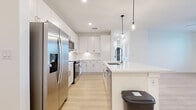 Located in Daytona Beach, Florida, this well-designed single-floor residence offers three bedrooms, three bathrooms, and three closets within a thoughtfully laid-out floor plan. The interior is defined by a clean, modern aesthetic, with light wood-tone flooring and crisp white walls flowing consistently throughout the space.

The kitchen is a standout feature, showcasing white flat-panel cabinetry, a white quartz waterfall island with an undermount sink, and a full suite of stainless steel appliances including a French door refrigerator, electric range, built-in microwave, and dishwasher. Pendant lighting above the island and recessed ceiling lights enhance both functionality and ambiance.

The bedrooms are bright and well-proportioned, with large windows that invite natural light and offer views of the surrounding greenery. Each room features the same warm wood-tone flooring and clean white finishes, creating a calm, cohesive atmosphere. Each bedroom is complemented by a dedicated closet equipped with wire shelving and hanging rods, maximizing storage efficiency.

The bathrooms maintain the home's modern theme, with white subway tile tub surrounds, clean white vanities, and brushed nickel hardware. The consistent use of light tones and quality finishes throughout creates a fresh, move-in-ready environment suited for comfortable everyday living.