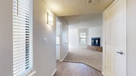 Located at 2600 W Ina Rd in Tucson, Arizona, this single-story residence offers a well-organized layout with a comfortable, neutral aesthetic throughout. The entryway features wood-look flooring and a wall sconce, transitioning seamlessly into the carpeted living room, which is anchored by a standout tile-surround fireplace with glass doors and a raised hearth. Natural light filters in through blinds-covered windows, creating a bright and welcoming atmosphere.

The kitchen is efficiently designed with white cabinetry, light stone countertops, and a full suite of black appliances including a refrigerator, electric range, microwave, and dishwasher. Wood-look flooring carries through the kitchen, which connects directly to an additional carpeted room brightened by a ceiling fan and ample natural light.

The bedrooms are carpeted and well-sized, each offering access to closet space. One bedroom includes a walk-in closet with built-in shelving, while another opens to a utility area with in-unit laundry. The bathrooms feature wood-look flooring, white tilework, and clean, simple fixtures. The primary bathroom offers a vanity with updated cabinetry and access to a spacious walk-in closet. Textured ceilings are present throughout, adding a classic residential character to the home.