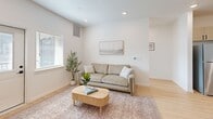 Located in Logan, Utah, this well-designed 2-bedroom, 2-bathroom single-floor unit offers a clean, modern aesthetic with a thoughtfully planned open-concept layout. The kitchen and living room flow seamlessly together, creating a connected and functional living space. The kitchen is outfitted with light wood cabinetry, black hardware accents, white quartz countertops, stainless steel appliances—including a full-size refrigerator, range, microwave, and dishwasher—and a central island with bar seating, ideal for casual dining or entertaining. Light hardwood-style flooring runs throughout the main living areas, adding warmth and continuity. The living room is bright and airy, benefiting from natural light through large windows with blinds. Both bedrooms feature soft carpet flooring and ample natural light, with the primary bedroom offering generous proportions and its own dedicated closet. The two bathrooms are finished with light wood vanities, white quartz countertops, black hardware, and hardwood-style flooring, maintaining the consistent modern design language found throughout the unit. Two closets provide practical storage. The overall ambiance is calm, clean, and contemporary, with a neutral color palette that enhances the sense of openness across the entire floor plan.