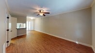 This two-story home offers a practical and comfortable layout across its two levels. The kitchen is a functional highlight, featuring white raised-panel cabinetry, dark granite-style countertops, a mosaic tile backsplash, and a full suite of stainless steel appliances including a range, microwave, dishwasher, and refrigerator. Track lighting illuminates the space, which transitions to tile flooring. A peninsula with a double basin sink separates the kitchen from the adjoining living areas.

The main living area is generously proportioned, featuring warm hardwood-style flooring, crown molding, a ceiling fan, and a window that allows natural light to filter in. A staircase connects to the second floor. The dining or secondary living space also features hardwood-style flooring, a ceiling fan, and access to an outdoor area through sliding doors.

The bedrooms are carpeted and offer a calm, neutral palette with ceiling fans and windows providing natural light. The bathroom includes a tub-shower combination, tile flooring, and a vanity with dark countertops. A dedicated utility room houses the water heater, washer/dryer hookups, upper white cabinetry, and an electrical panel, adding practical storage and functionality to the home.