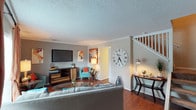 This two-story residence offers two bedrooms and one and a half bathrooms across a well-utilized floor plan. The main level features a living room with hardwood-style flooring, crown molding, and a staircase leading to the upper floor. A dedicated desk area near the stairs adds functional workspace to the living area. The adjacent dining area includes a pendant light fixture, crown molding, and a sliding glass door that draws in natural light and provides outdoor access.

The kitchen is equipped with dark cabinetry, granite-style countertops, a stainless steel refrigerator, and a range, with tile flooring and ample storage including a double-door pantry. A half bath on the main level features a granite-topped vanity.

Upstairs, a second living or flex space features a teal accent wall, ceiling fan, and carpeted flooring. Both bedrooms are carpeted and include ceiling fans and closets; one bedroom benefits from multiple windows offering natural light, while the other includes a walk-in closet. A full bathroom with tiled walls and a combined vanity serves the upper level. Throughout the home, textured ceilings and neutral tones create a cohesive, inviting atmosphere.