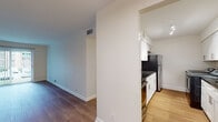 This single-floor residence offers a clean, modern aesthetic defined by light-toned walls, crisp white trim, and warm hardwood flooring that flows consistently throughout the living spaces. The galley-style kitchen is a standout feature, outfitted with white shaker cabinetry, dark granite countertops, a white subway tile backsplash, stainless steel appliances including a refrigerator, and track lighting overhead. Notably, the kitchen also accommodates an in-unit washer and dryer, adding a high level of convenience. The open living and dining area is generously proportioned, bathed in ambient light, and provides a seamless connection to the kitchen via a half-wall partition. The bedrooms are well-sized, each featuring hardwood floors and windows that bring in natural light with views of the surrounding neighborhood. One bedroom includes direct access to a private bathroom and a closet with louvered doors. The bathrooms are finished with neutral stone-toned countertops, undermount sinks, brushed nickel fixtures, and a tub-shower combination with classic white subway tile surround. The overall layout is practical and cohesive, offering a bright, move-in-ready living environment with thoughtful finishes throughout.