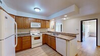 Located at 215 W Cascade Ave in River Falls, Wisconsin, this single-floor, three-bedroom, one-bathroom residence offers a practical and comfortable layout across a well-utilized footprint. Light wood-style flooring flows throughout the main living areas and bedrooms, creating a bright and cohesive aesthetic.

The kitchen is a functional centerpiece of the home, outfitted with warm oak cabinetry extending to the ceiling for generous storage, laminate countertops, and white appliances including a refrigerator, electric range, built-in microwave, and dishwasher. A peninsula counter provides additional prep space and opens toward the main living area.

The three bedrooms are well-proportioned, with the primary bedroom featuring a ceiling fan, a window with a pleasant outdoor tree view, and a built-in wall-mounted desk surface. The additional bedrooms include light-filled spaces with closet access and wood-style flooring. Closet storage is available in multiple areas, including a linen-style closet with wire shelving located within the bathroom corridor.

The bathroom includes a vanity with oak cabinetry, tile flooring, and an adjacent linen closet with multi-tier wire shelving. A dedicated laundry area with tile flooring accommodates a full-size washer and dryer, complemented by overhead shelving and utility access. The layout provides a logical, connected flow between all rooms.