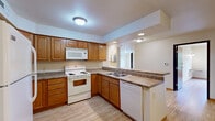 Located at 215 W Cascade Ave in River Falls, Wisconsin, this single-floor, three-bedroom, one-bathroom residence offers a practical and comfortable layout across a well-utilized footprint. Light wood-style flooring flows throughout the main living areas and bedrooms, creating a bright and cohesive aesthetic.

The kitchen is a functional centerpiece of the home, outfitted with warm oak cabinetry extending to the ceiling for generous storage, laminate countertops, and white appliances including a refrigerator, electric range, built-in microwave, and dishwasher. A peninsula counter provides additional prep space and opens toward the main living area.

The three bedrooms are well-proportioned, with the primary bedroom featuring a ceiling fan, a window with a pleasant outdoor tree view, and a built-in wall-mounted desk surface. The additional bedrooms include light-filled spaces with closet access and wood-style flooring. Closet storage is available in multiple areas, including a linen-style closet with wire shelving located within the bathroom corridor.

The bathroom includes a vanity with oak cabinetry, tile flooring, and an adjacent linen closet with multi-tier wire shelving. A dedicated laundry area with tile flooring accommodates a full-size washer and dryer, complemented by overhead shelving and utility access. The layout provides a logical, connected flow between all rooms.
