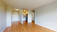Located at 1379 Princess St in Kingston, Ontario, this one-bedroom, one-bathroom unit offers a practical and well-organized layout across a single floor. Warm-toned hardwood flooring runs throughout the main living areas, lending a cohesive and inviting feel to the space.

The open living area is bright and airy, benefiting from a large window that frames pleasant views of surrounding greenery. A radiator unit provides in-suite heating, and neutral grey walls create a clean, versatile backdrop. The kitchen is efficiently designed with white cabinetry, a tile backsplash, stainless steel appliances including a range and dishwasher, and a functional countertop workspace.

The bedroom is a comfortable, well-proportioned room featuring hardwood flooring, a window with natural light and outdoor tree views, and its own radiator. Multiple closets throughout the unit offer generous storage options. The bathroom includes a full soaker tub with a tiled surround, a white vanity with storage, and distinctive earth-toned floor tiling that adds character to the space.

An entrance area provides a welcoming transition into the unit. Overall, the space maintains a clean, neutral aesthetic with practical finishes suited to comfortable everyday living.