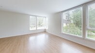 Located at 747 Hanami Ln NE on scenic Bainbridge Island, Washington, this well-appointed 3-bedroom, 3-bathroom residence offers a thoughtfully designed single-level layout. The open-concept kitchen and living area serves as the heart of the home, featuring warm wood cabinetry, stainless steel appliances including a refrigerator, range, and microwave, a large center island with pendant lighting and a built-in sink, and light hardwood flooring throughout. The living room benefits from track lighting and direct sightlines to the kitchen, creating a cohesive and functional shared space. Large windows throughout the unit frame lush Pacific Northwest greenery, flooding each room with natural light. The primary bedroom offers a comfortable, carpeted retreat, while additional bedrooms feature either hardwood or carpeted floors and generous windows with outdoor views. Each bedroom is served by its own closet, and the unit includes two dedicated closet spaces for extra storage. The bathrooms are finished in a clean, contemporary style, with wood-toned vanities, white quartz countertops, and walk-in showers with chrome fixtures. A stacked washer and dryer unit is conveniently located within the residence. The overall aesthetic is modern and bright, with a neutral palette that enhances the sense of openness throughout.