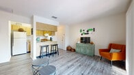 Located at 1108 Markstown Ln in Lakeland, Florida, this single-story residence offers a practical and well-organized layout designed for comfortable everyday living. The open-concept living and kitchen area forms the heart of the home, where wood-grain laminate flooring flows throughout, lending a clean and cohesive aesthetic. The kitchen features warm wood cabinetry, a breakfast bar with seating, a full-size refrigerator, and a stainless steel sink, making it both functional and accessible from the living space.

The living area is generously proportioned, allowing for flexible furniture arrangements, and is anchored by a large sliding glass door that fills the space with natural light and provides direct access to a private outdoor patio overlooking greenery. The seamless indoor-outdoor connection enhances the overall sense of openness.

The bedrooms are carpeted for comfort and feature windows with blinds that allow for natural light while maintaining privacy. The bathroom is clean and straightforward, featuring a single-sink vanity with a large mirror, white cabinetry, and wood-style tile flooring. Overall, the space offers a bright, functional environment in a residential Lakeland neighborhood.