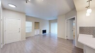 Located at 12500 Merit Dr in Dallas, TX, this well-appointed two-bedroom, two-bathroom residence offers a thoughtfully designed single-floor layout. Light-toned hardwood-style flooring flows consistently throughout the space, creating a cohesive and clean aesthetic. The open-concept kitchen and living area forms the heart of the home, where a curved peninsula with a quartz countertop and undermount sink serves as a natural gathering point. The kitchen is equipped with stainless steel appliances—including a refrigerator, range, and microwave—complemented by white cabinetry and a classic gray brick tile backsplash. Pendant lighting adds a finished touch overhead. The living room is bright and spacious, featuring a fireplace with a white surround, a built-in niche with cabinetry, and large vertical-blind windows that invite natural light. The primary bedroom includes dual mirrored sliding closets and a ceiling fan, while a separate walk-in closet provides additional storage. The second bedroom is generously sized with a large window. Both bathrooms are clean and functional, with one featuring a full soaking tub with tiled surround. A dedicated laundry area and six closets throughout round out the practical storage offerings of this well-organized Dallas residence.